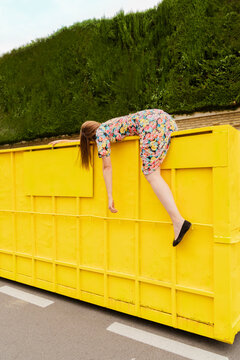 Exhausted woman hanging over edge of yellow container