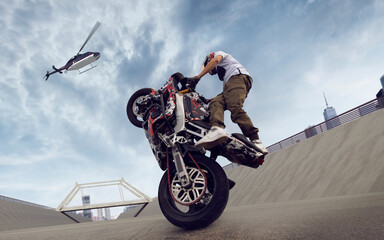 Moto rider making a stunt on his motorbike. Biker doing a difficult and dangerous stunt.