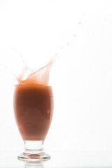 Orange red drink in glass ice fall splash