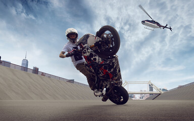 Moto rider making a stunt on his motorbike. Biker doing a difficult and dangerous stunt.