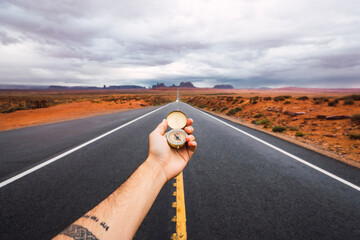 USA, Utah, Hand holding compass over road to Monument Valley