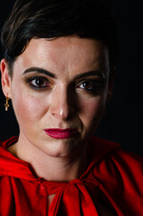 beautiful woman red cloak with red flowers roses in studio. Woman Red Riding Hood. Dramatic and fantastic shooting,fashionable toning. Like a princess