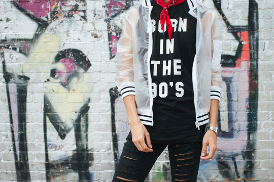 Fashionable young man wearing t-shirt with saying 'Born in the 90s' and rainjacket, partial view