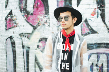 Fashionable young man with hat and sunglasses wearing translucent rainjacket