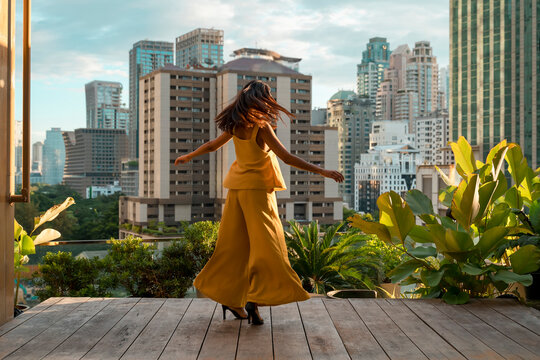 Back view of woman dancing on roof terrace, Bangkok, Thailand