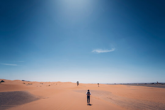 Lonely man with hat standing in the dunes of the desert of Morocco