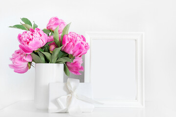 Pink peony in white vase, gift and photo frame. Space for text.