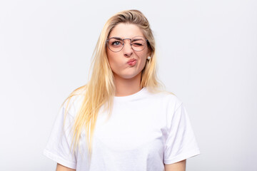 young pretty blonde woman looking happy and friendly, smiling and winking an eye at you with a...