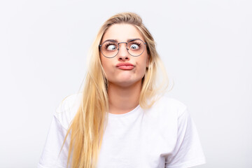 young pretty blonde woman looking goofy and funny with a silly cross-eyed expression, joking and...