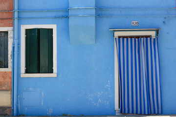 Open door and blue whall on the street with an open window and opened window shutters