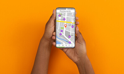 African American girl holding cellphone with map and restaurant navigation pointers, orange...