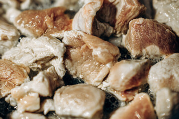 Pieces of meat are fried in oil. Large clan. Selective focus