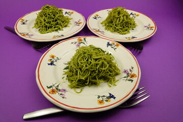 Faience plates with pesto pasta on a purple background