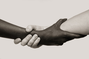 Black-and-white human arms wrapped tightly around each other . The concept of combating racism, friendship and respect .Selective focus, close-up, black and white photography, isolated background.