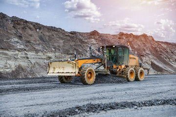 motor grader levels the ground on background of sandy slope on the road construction 