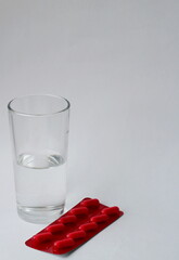 medicines, pills and a glass of water on a white background