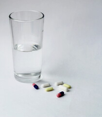 
medicines, pills and a glass of water on a white background