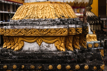 Fundaments of a stony and golden painted stupa in front of a protecting wall in a temple in Siamese Lao PDR, Southeast Asia