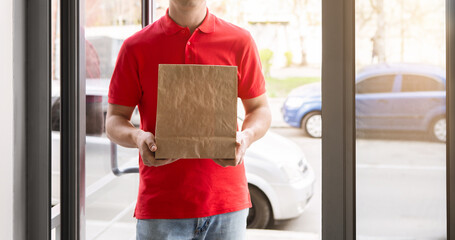 Gentle delivery package with fragile things. Courier holds paper parcel bag