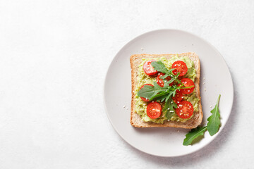 Avocado rye bread toast with cherry tomatoes and arugula.