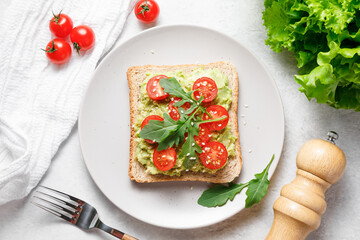 Avocado sandwich with cherry tomatoes and arugula.