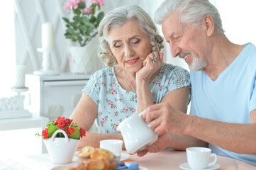 Portrait of mature couple drinking tea with cookies