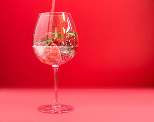 Bright juicy selected strawberries in a large glass with soda.