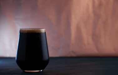 stout beer in a low glass on a dark table with copy space