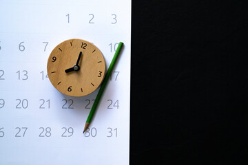 close up of alarm clock and calendar on the black background, planning for business meeting or travel planning concept