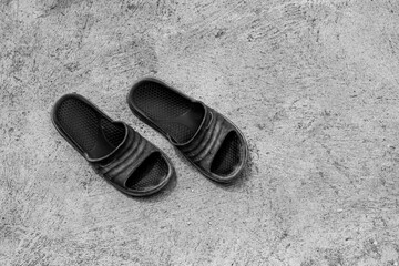 A pair of old black rubber sandals on the cement floor.