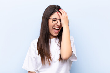 young pretty woman laughing and slapping forehead like saying d‚Äôoh! I forgot or that was a...