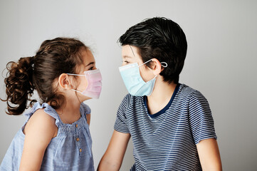 two child playing with mask in coronavirus times. brothers trying to put on a surgical mask to go outside in the confinement due to the coronavirus. social distancing measures to avoid contagion