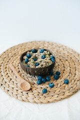 oatmeal porridge in bowl with fresh blueberries.Healthy vegan Breakfast cereals, against background of brown natural seaweed napkin,natural wooden bamboo spoon.Concept of clean food,healthy lifestyle