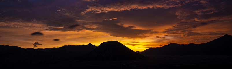 Obraz premium Stunning dramatic sunset behind the silhouette of the mountain range that includes Mount Semeru, Mount Batok and Mount Bromo in East Java, Indonesia...