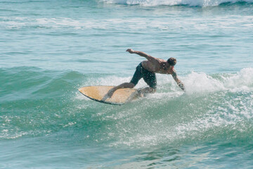 Handsome man surfing a wave in the mediterranean sea on an orange surfboard