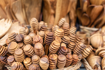 Traditional Cretan handmade olive wood honey dipper objects made of olive wood, souvenir market store. - obrazy, fototapety, plakaty