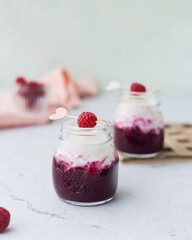 Two jar with smoothie from berries and milk with raspberry as garnish.