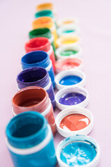 Jars of gouache, stand in a row. Side view. Concept of choice. Many colors, variety.