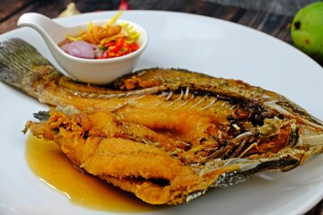 Deep-fried Sea bass with fish sauce on white plate served with spicy mango salad.
