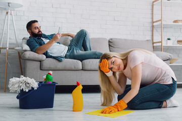 Sexism and disrespect for wife. Man lies on couch and typing on phone, sad woman clings to her head...