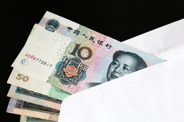 Yuan bills in white envelope on the black background. Chinese economy, income, bonus or bribe...