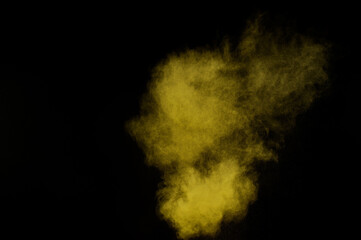 Yellow powder explosion on black background. Colored powder cloud. Colorful dust explode. Paint  Holi.