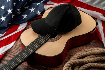 Freedom and american country and blues music festival concept with USA flag and acoustic guitar with a black cap on top and cowboy lasso placed on a dark wood vintage table