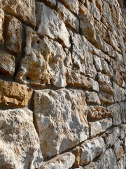 Sandstone Wall Masonry at a Side Angle View of Stone Shape and Rough Texture in Light and Shadow - obrazy, fototapety, plakaty