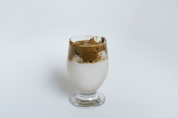 Dalgona Coffee in a clear glass on a white background. 