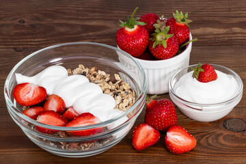 bowl of oat granola with yogurt, fresh strawberry on wooden background for healthy breakfast with copy space.