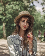 The portrait of young beautiful woman in hat and dress smiling in the park.