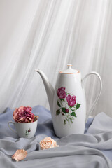 Still life: teapot with small cup and dried roses