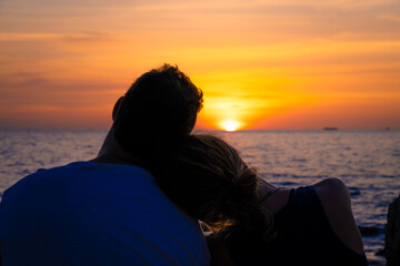 Loving couple looking the sunset on the beach.