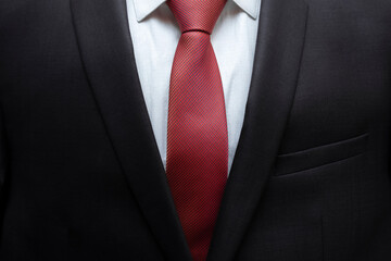 Closeup of black business suit with white shirt and red tie. Businessman in a black suit with a red tie. Business concept.